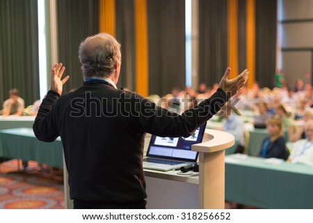 Speaker at Business Conference with Public Presentations. Audience at the conference hall. Business and Entrepreneurship concept. Rear view. Horisonatal composition. Background blur.