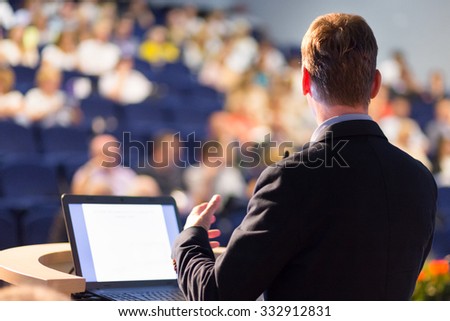 Speaker at Business Conference with Public Presentations. Audience at the conference hall. Entrepreneurship club. Rear view. Horisontal composition. Background blur.