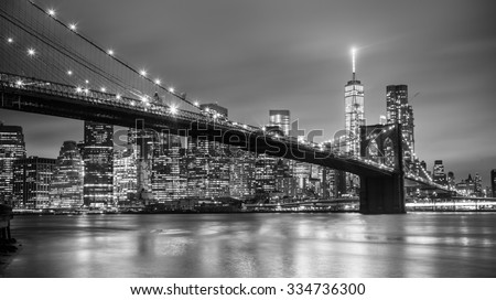 Brooklyn bridge and New York City Manhattan downtown skyline at dusk with skyscrapers illuminated over East River panorama. Copy space. Black and white image.