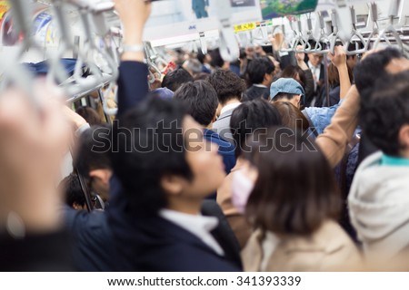 Passengers traveling by Tokyo metro. Business people commuting to work by public transport in rush hour. Shallow depth of field photo. Horizontal composition.