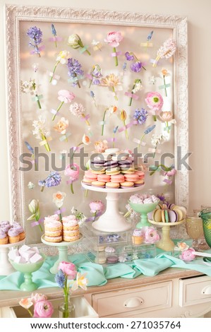 Dessert table with a macaroons composition - colorful pyramid, cupcakes, flowers