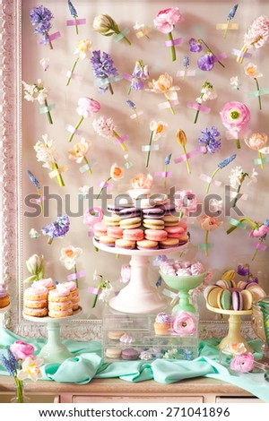 Dessert table with a large macaroons composition - pyramid in pink, decorated with flowers.