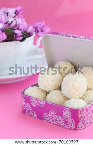 white candies into a pink box, white cup with purple spring flowers  on pink background