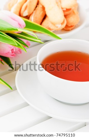 White cup saucer, pastry  and a pink tulips on white background