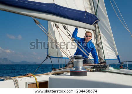 Sailor stays at his yacht, witch is going on the sea on full sails.