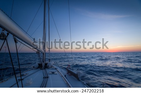Sailing boat, open sea and sundown at the horizon
