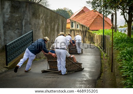 Toboggan riders moving traditional cane sledge downhill on the streets of Funchal. Monte park, Madeira island, Portugal