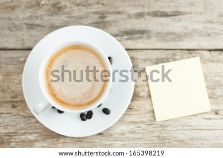 Overhead view of hot coffee drink with hand and sticky note with pencil