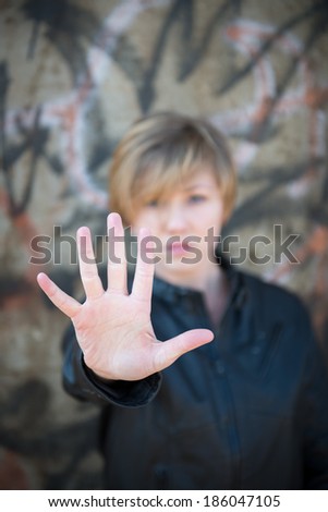 Scared teen girl holds up hand towards camera to say \'stop\'