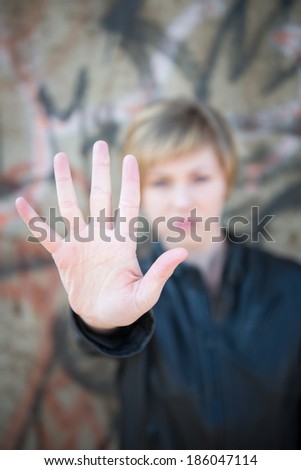 Scared teen girl holds up hand towards camera to say 'stop'