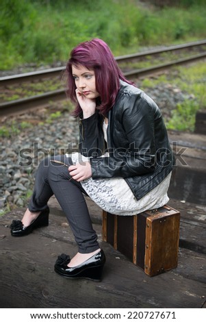 Sad runaway teen girl waits for train to escape her problem
