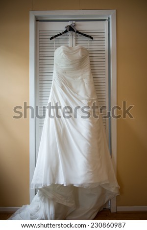 Beautiful wedding dress on hanger, in natural light from window