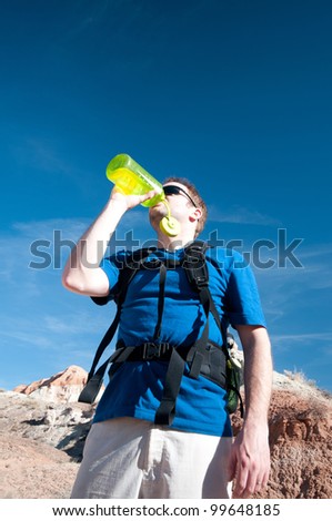 Man hydrates in desert, on hot, sunny day