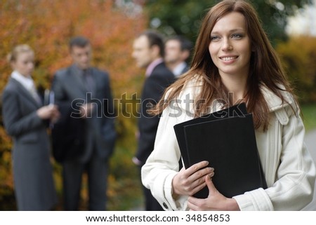 Business woman in an outdoor environment with her colleagues on the background