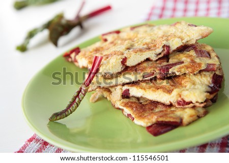 Piece of omelette with red chard on green plate