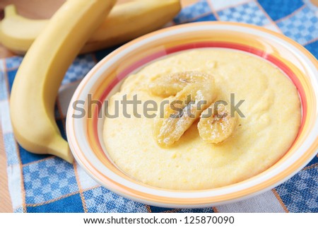 Milk porridge of maize grain with fried bananas in bowl