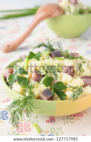 Mashed potatoes with pieces of herring, dill, parsley and chives in bowl