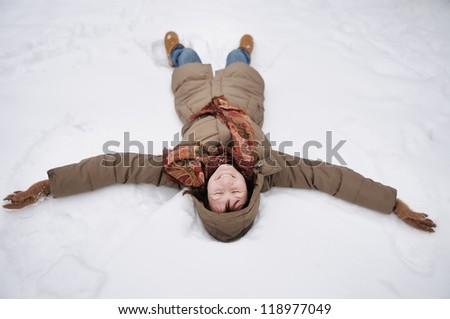 Winter fun - snow angel - happy middle age woman playing in snow