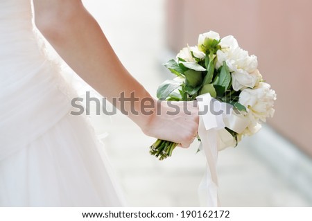 Bride holding wedding flowers bouquet, focus on hand