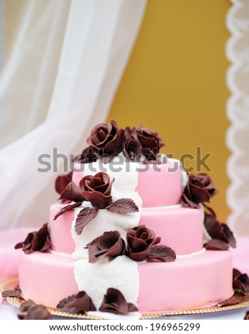 Delicious pink wedding cake decorated with brown cream roses