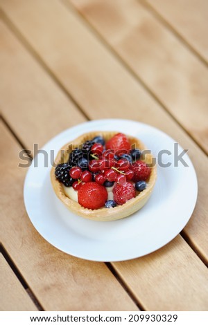 Custard fruit tart on white plate in the outdoors cafe