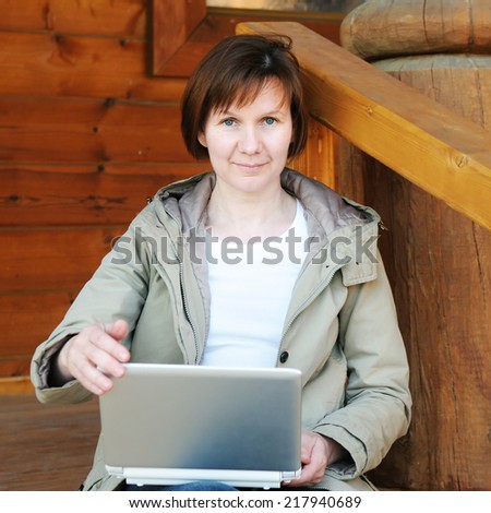 Woman with laptop sitting on wooden porch