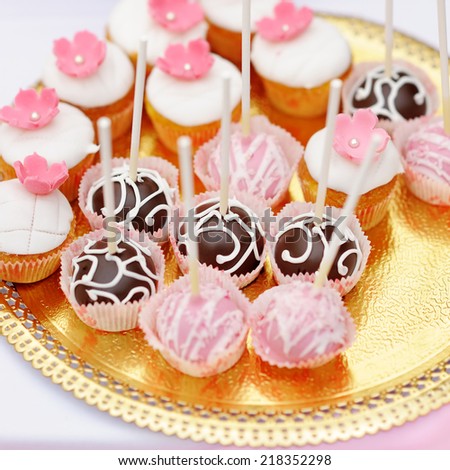 Chocolate and creamy pop cakes and cupcakes on golden plate