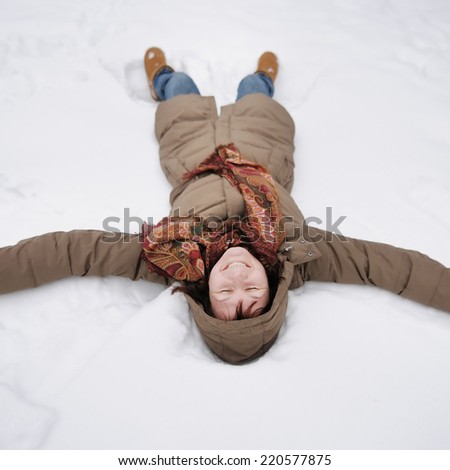 Winter fun - snow angel - happy middle age woman playing in snow