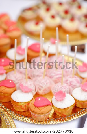 Pink pop cakes and cupcakes on golden plate
