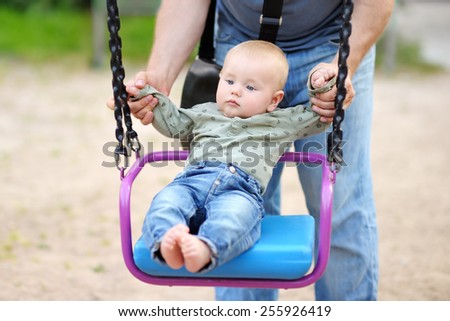 Father and his little son having fan on a swing at summer day