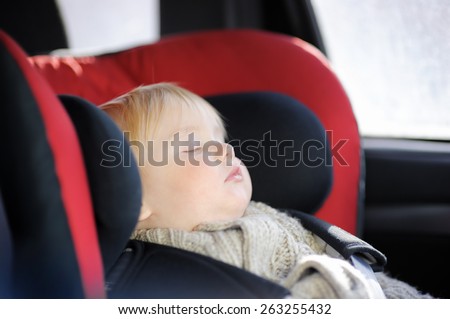 Portrait of sweet toddler boy sleeping in car seat