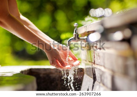 Closeup photo of woman washing hands in a city fountain