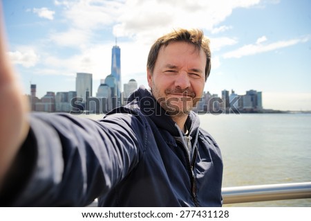 Middle age man taking a self portrait (selfie) with Manhattan skyscrapers in New York City
