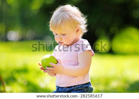 Beautiful toddler boy eating fresh bio green apple