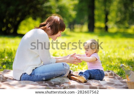 Beautiful young woman and her adorable little son having a picnic in sunny park