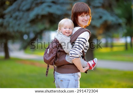 Young mother with her toddler child in a baby carrier