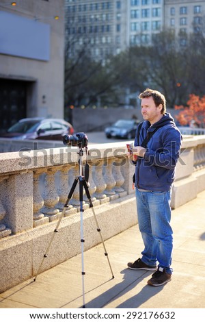 Middle age photographer taking photo with professional digital camera outdoors
