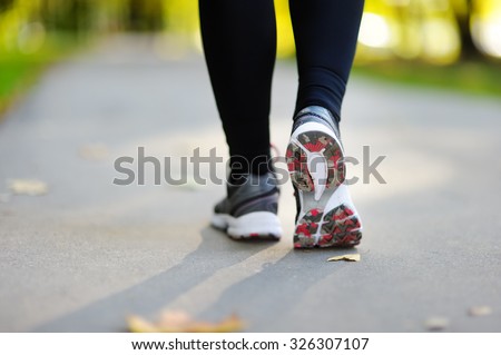 Runner feet running on road closeup on shoe. Woman fitness jog workout, welness concept