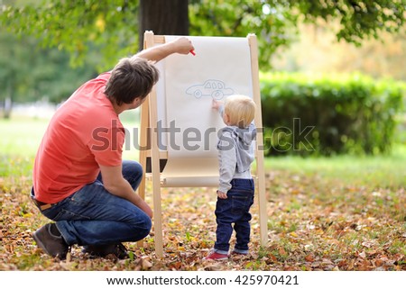 Middle age father and his toddler son drawing car