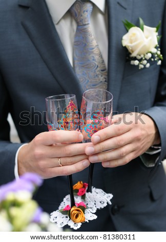 stock photo Groom is holding painting wedding champagne glasses