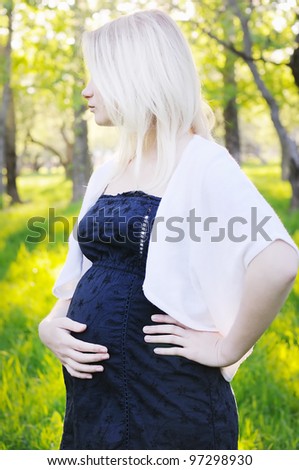 Beautiful young pregnant woman in park