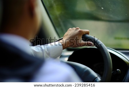 Man\'s hand on the steering wheel of a car