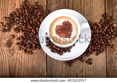Coffee cup Cappuccino on old wooden table. Heart shape foam, top view.