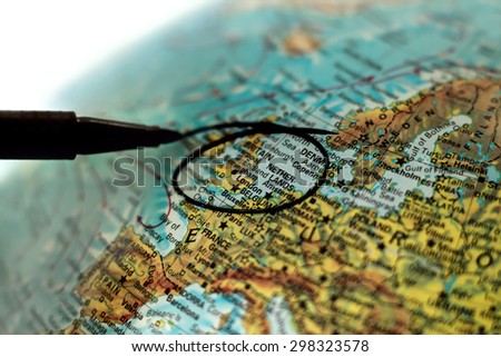 A black pen circles the United Kingdom, the first industrialized nation in the world, to highlight it as a point of interest on a three dimensional globe on a white background.