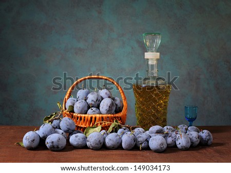 Plums in a wicker basket and plum brandy