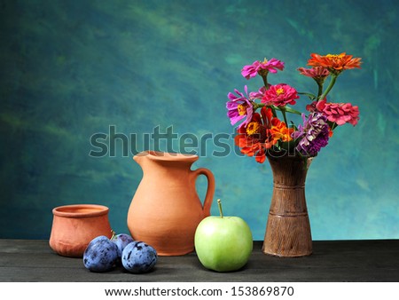 Ceramic jug and fruits and flowers in a vase