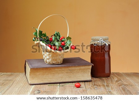 Fruit of dog rose in wicker baskets and books on the table