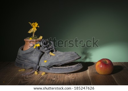 Old shoes and dried flowers in a ceramic vase