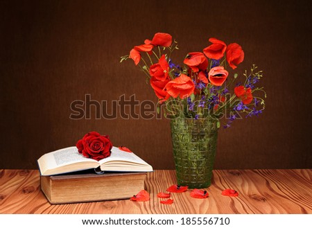 Poppies in a vase of glass and books on the table