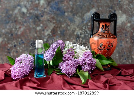Lilac and perfume in glass bottle on the table